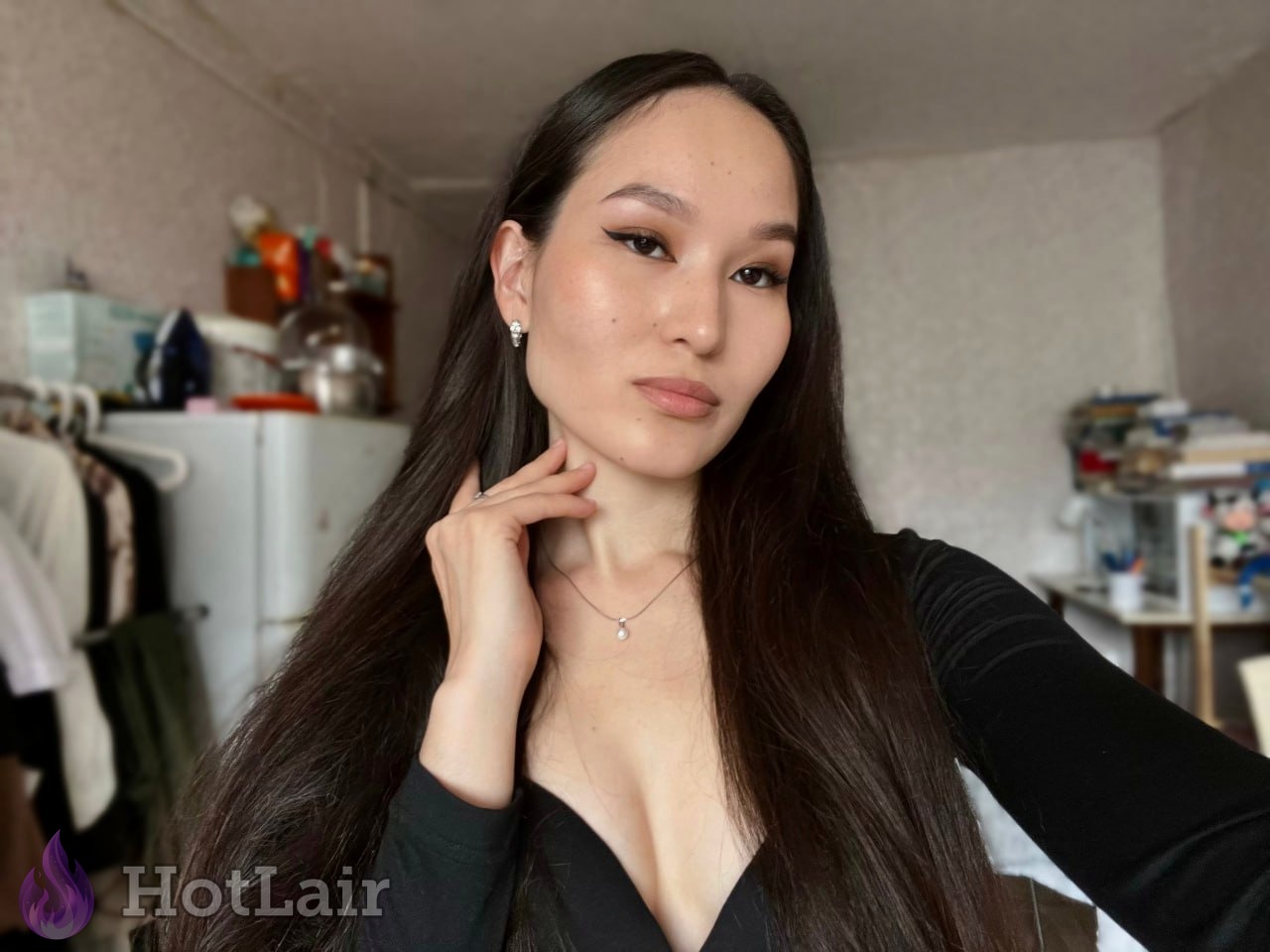 Gorgeous long-haired Asian girl in black low-cut top giving intense seductive gaze