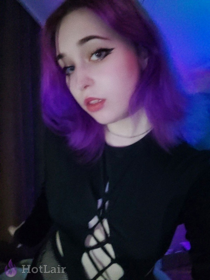 Seductive purple-haired girl with dramatic makeup in black cut-out top
