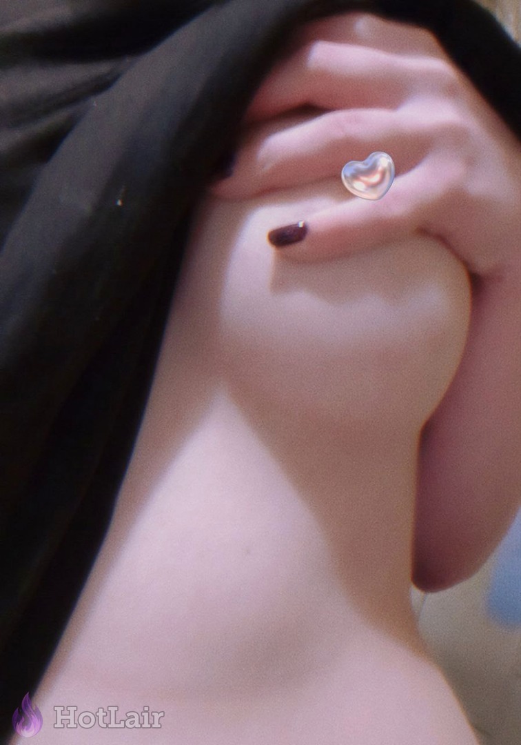 Close-up of soft breast squeezed by hand wearing heart-shaped ring