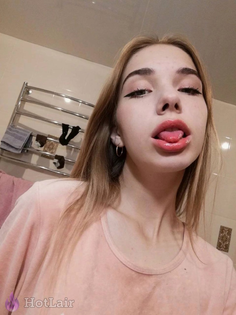 Seductive blonde taking mirror selfie sticking her tongue out playfully in bathroom