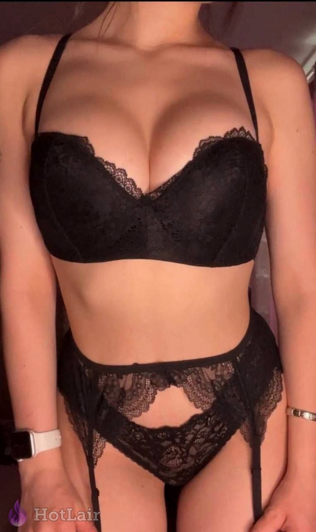 Gorgeous brunette with huge natural breasts in black lace lingerie and garter straps posing seductively, hands on hips