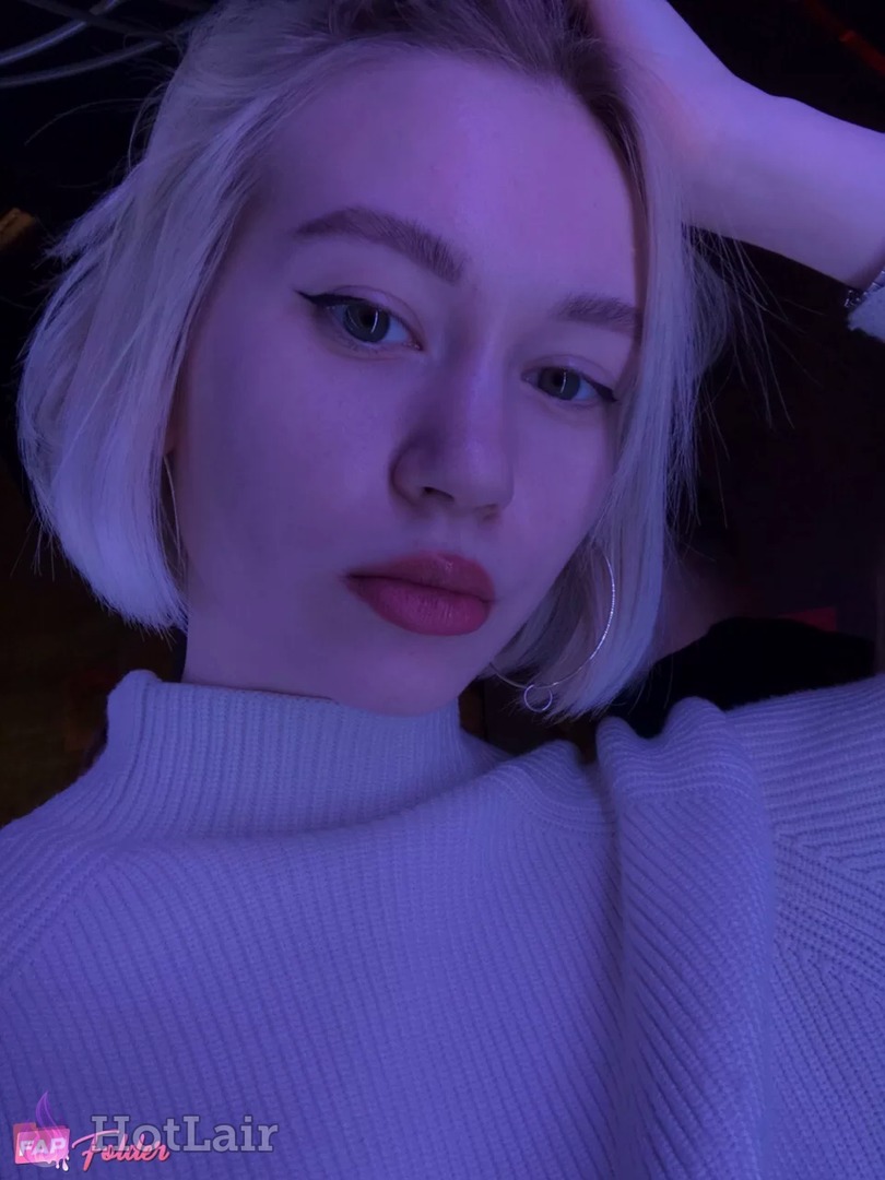 Close-up portrait of blonde woman with short bob haircut in white turtleneck sweater under purple neon lighting, seductive gaze