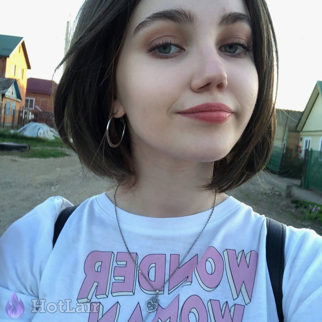 Cute brunette with bob haircut smiling in outdoor selfie wearing white t-shirt