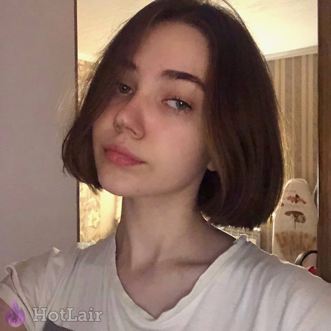 Attractive girl with short brown hair taking a flirty indoor mirror selfie