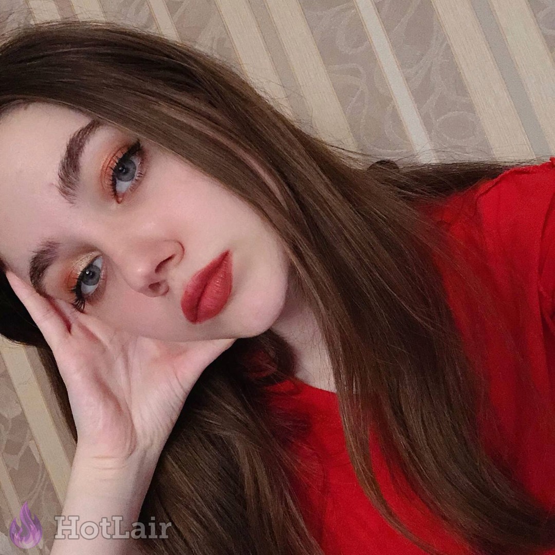 Gorgeous brunette with red lipstick lying down in red top, seductive close-up portrait