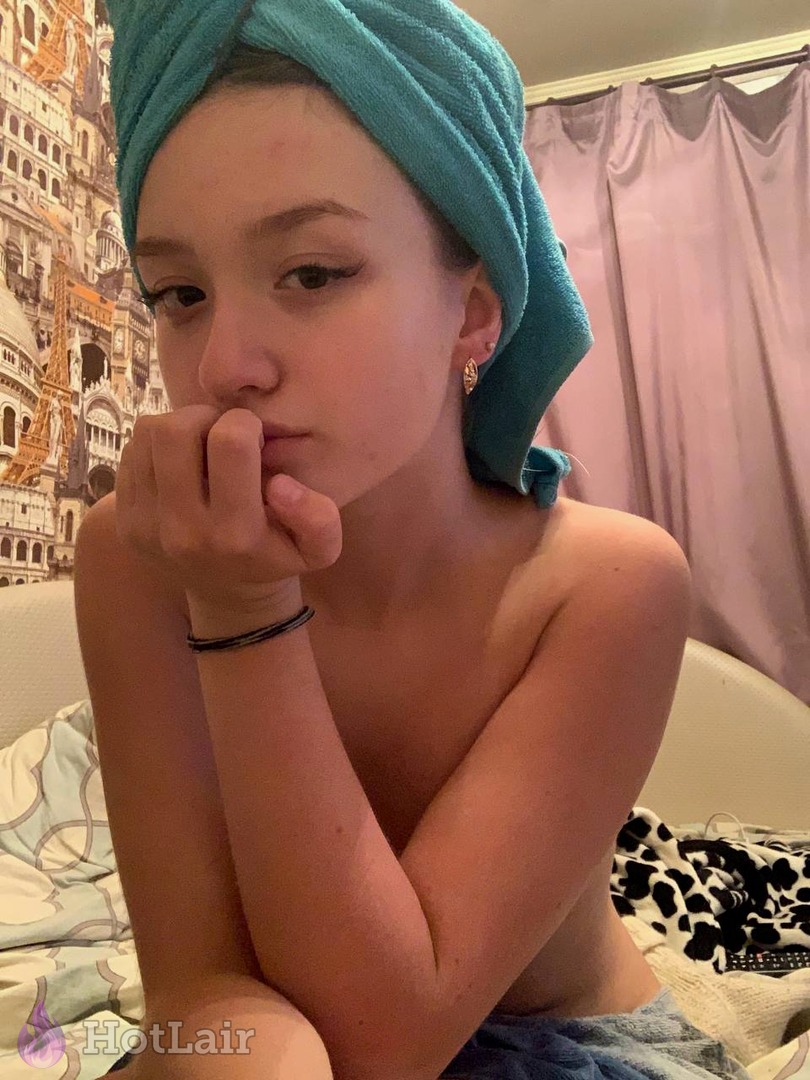 Pretty girl with turquoise towel on head posing topless on bed after shower