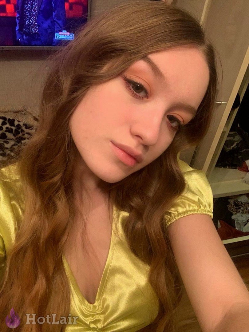 Stunning brunette in shiny yellow satin top taking seductive close-up selfie