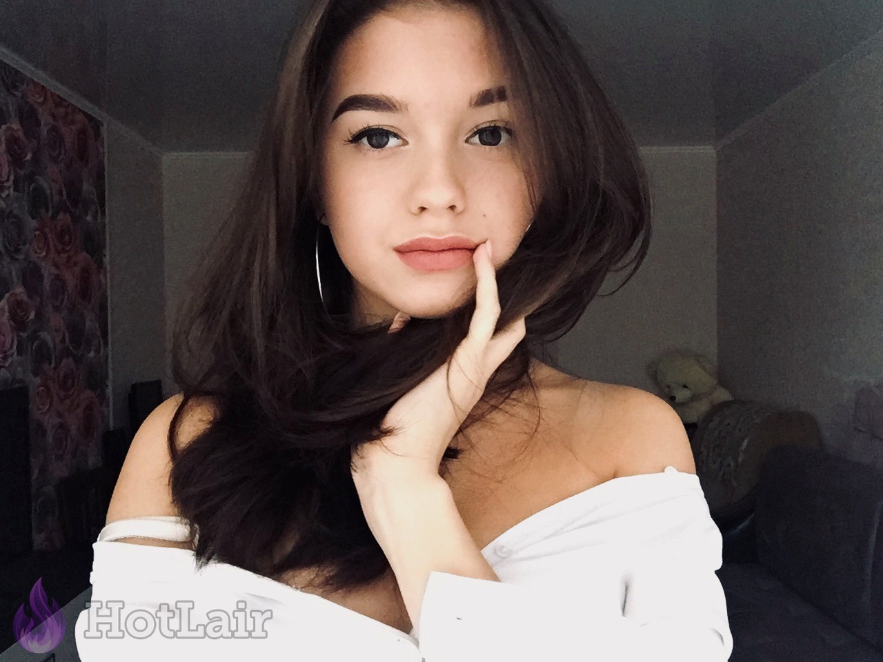 Gorgeous young brunette with long dark hair in white off-shoulder top close-up portrait