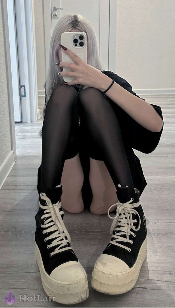 Seductive silver-haired beauty in sheer black pantyhose and chunky platform sneakers takes a teasing mirror selfie on the floor