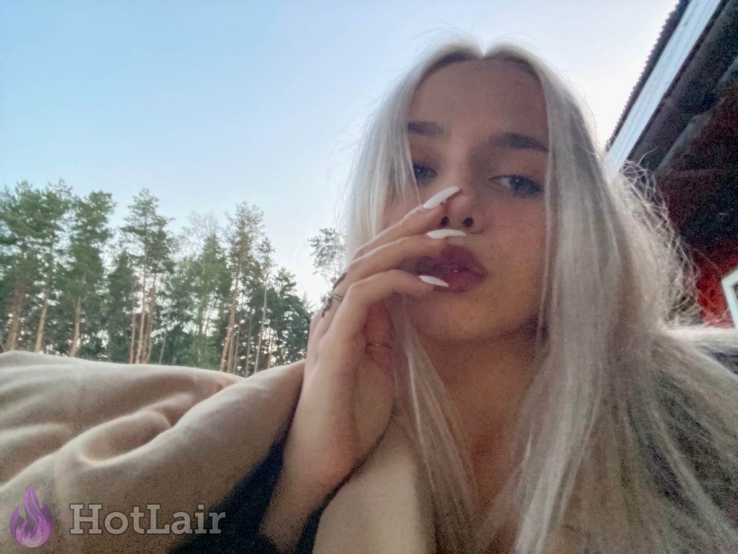 Beautiful platinum blonde takes outdoor selfie with long flowing hair and perfect makeup