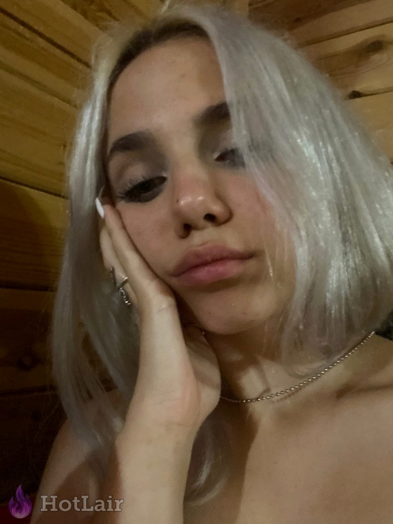 Pretty silver-haired girl rests face on hand in intimate close-up portrait