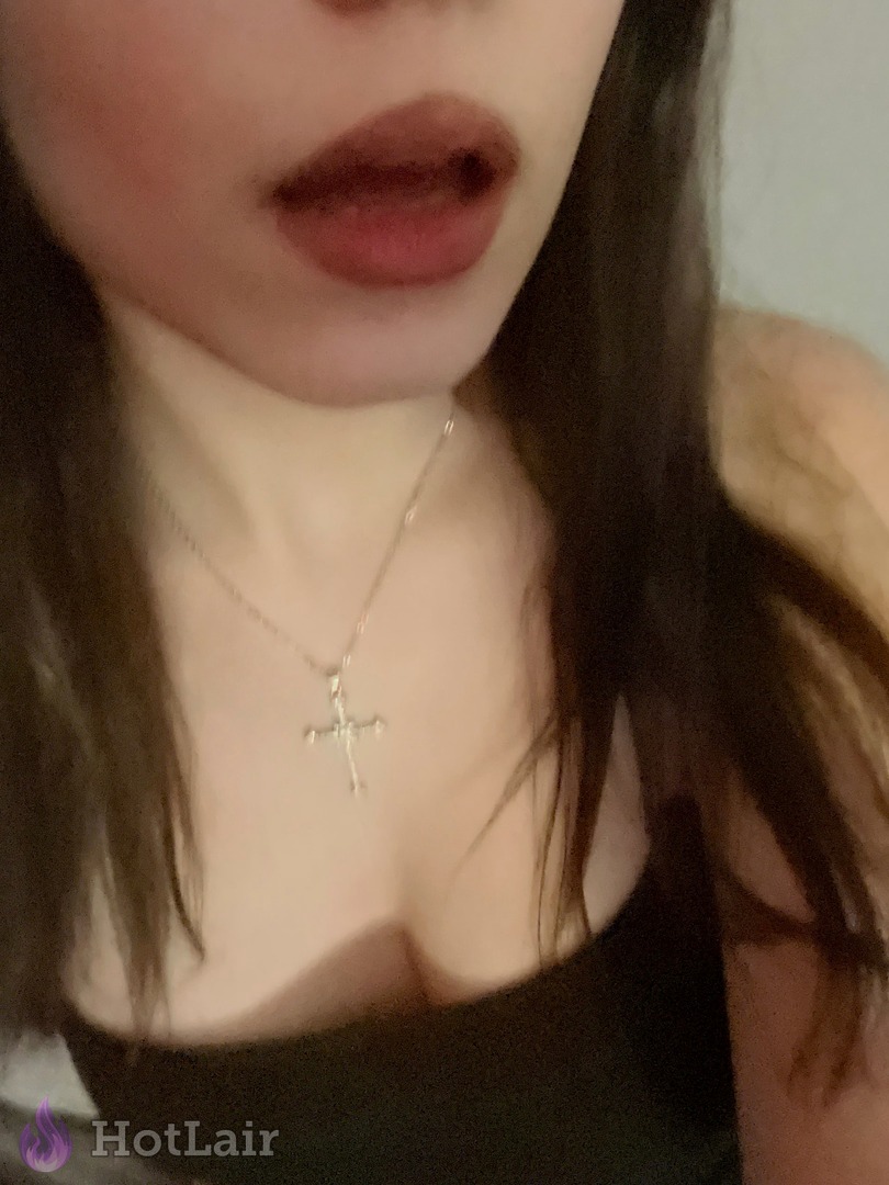 Seductive close-up of brunette’s lips, neck and deep cleavage with silver cross necklace