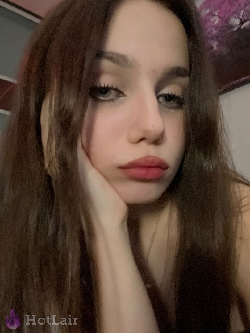 Gorgeous long-haired brunette rests chin on hand in soft close-up portrait