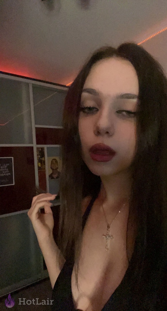 Alluring brunette in deep cleavage black top with cross necklace gives sultry stare