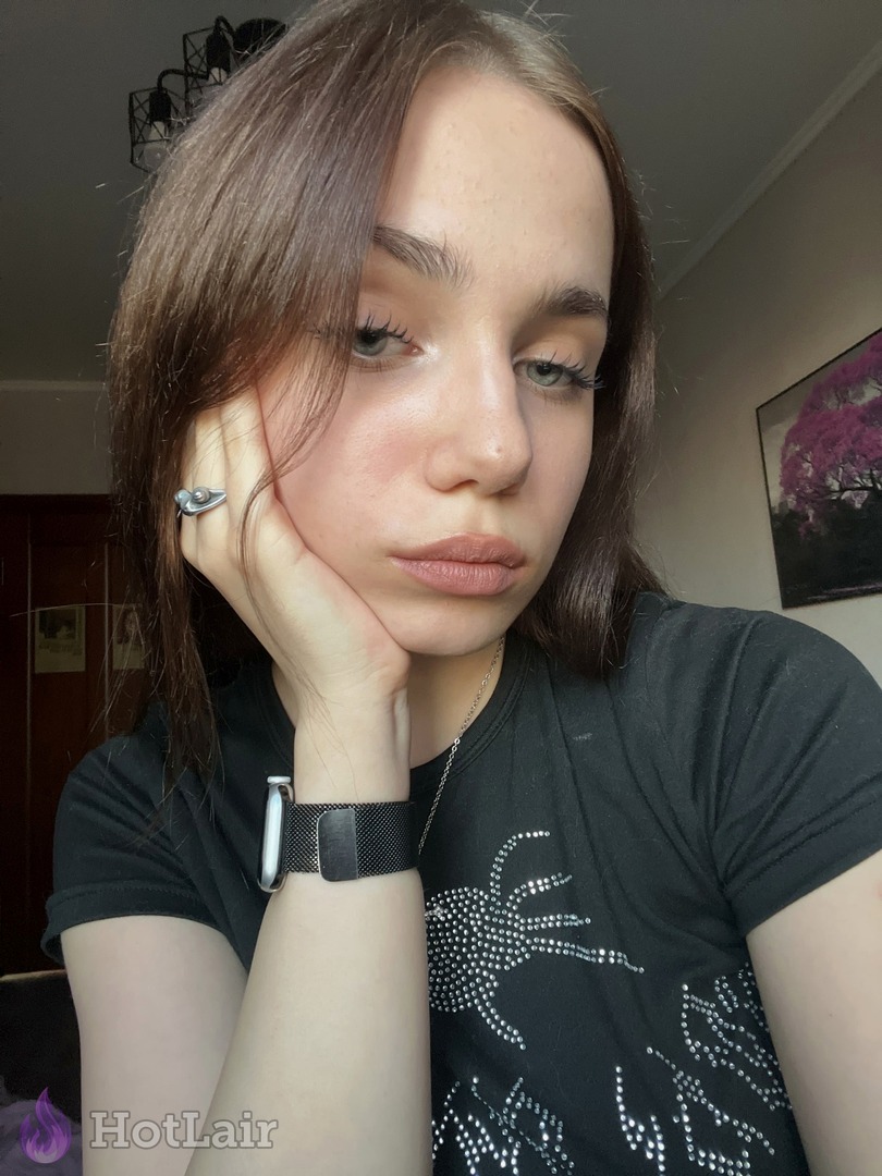 Pretty brunette in black rhinestone t-shirt rests cheek on hand in casual portrait