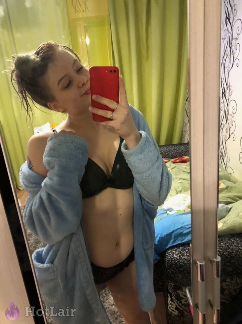 Cute brunette in black bra and blue bathrobe taking mirror selfie with red phone