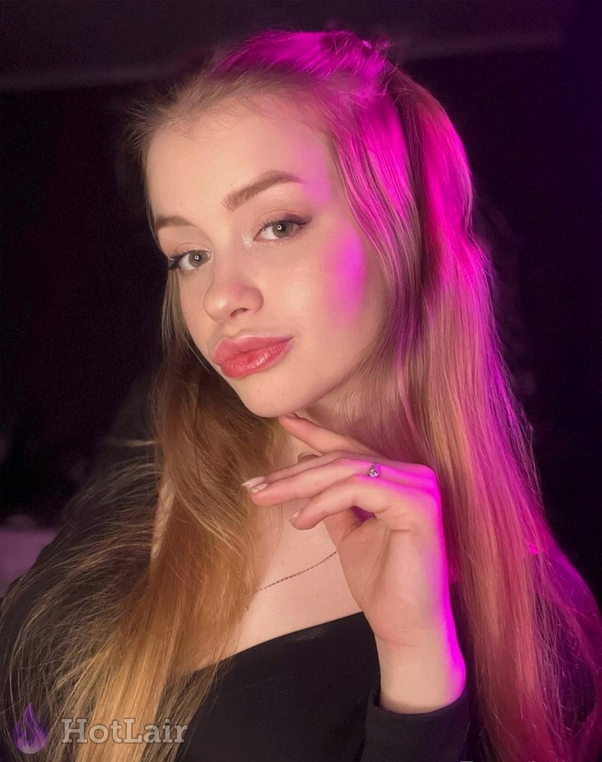 Gorgeous blonde with long hair posing seductively under pink neon lighting