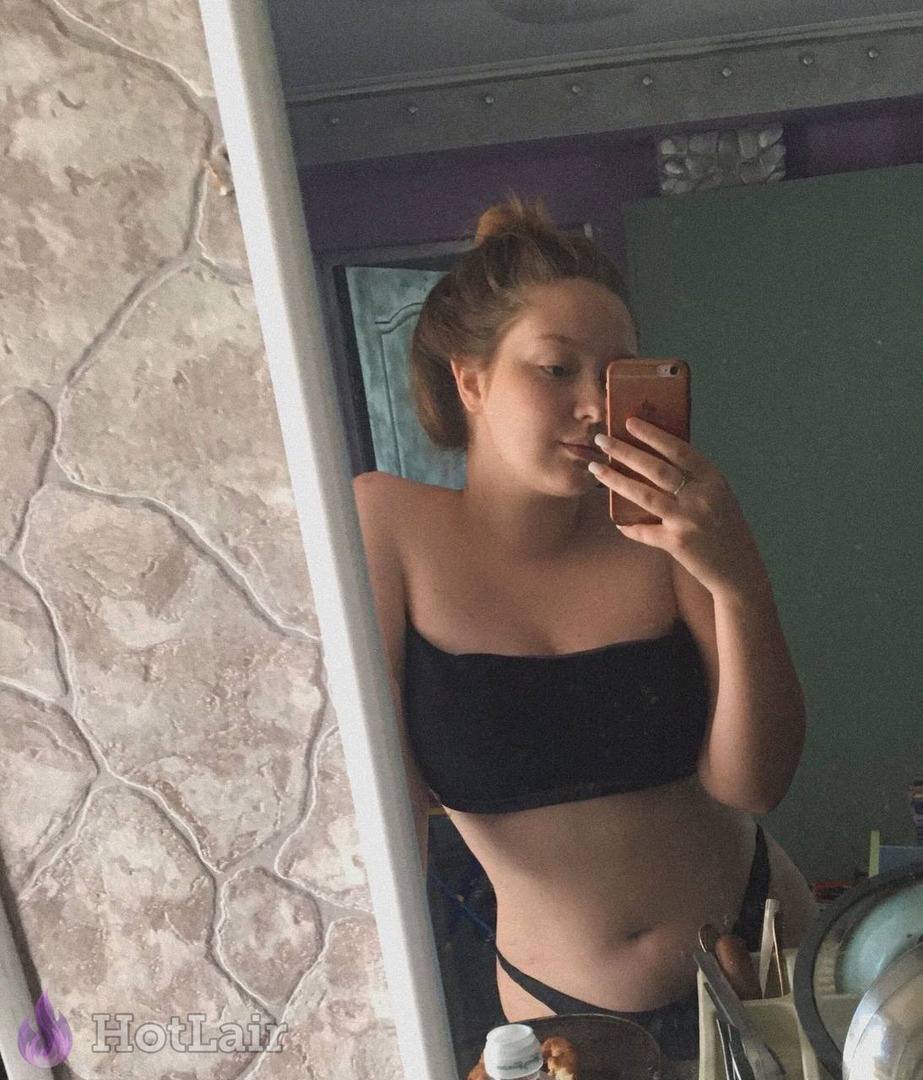 Curvy young woman taking mirror selfie in black tube top and panties