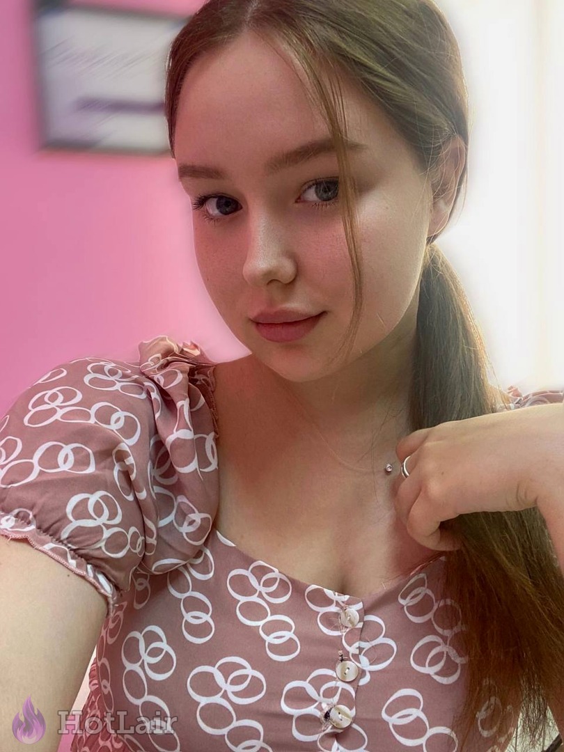 Pretty young woman with long brown hair in cute patterned top taking flirty close-up selfie