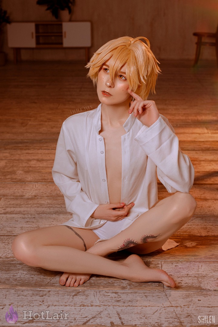 Cute short-haired blonde cosplayer in unbuttoned white shirt sitting sensually cross-legged on wooden floor