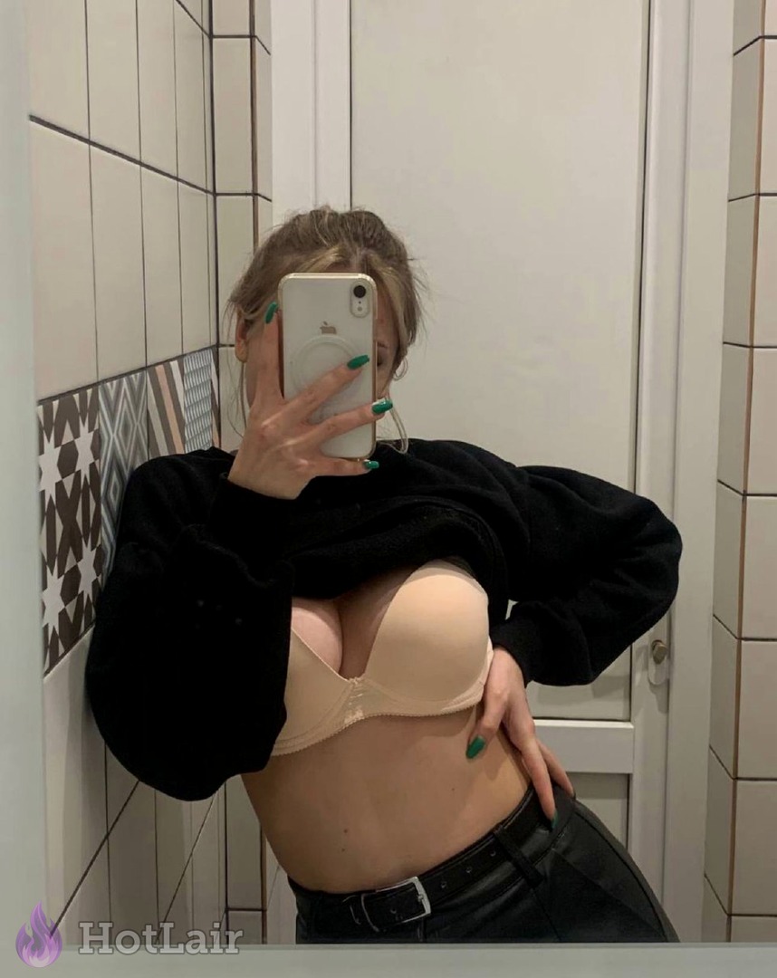 Busty woman in beige push-up bra and black sweater taking mirror selfie in bathroom
