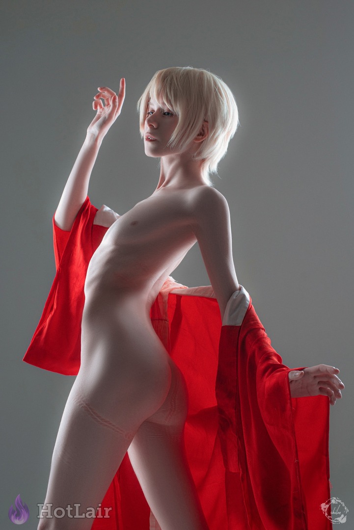 Elegant artistic nude slim blonde with short platinum hair draped in red fabric in dramatic studio lighting