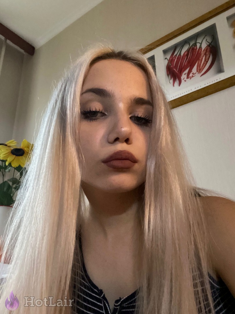 Beautiful platinum blonde with long hair and matte lipstick looking straight at camera in stylish striped top, intimate selfie