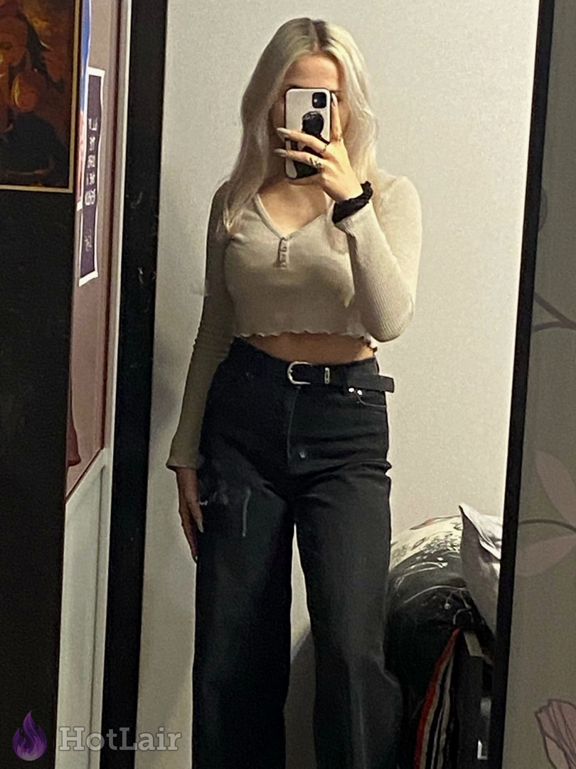Full-length mirror selfie of sexy platinum blonde in beige crop top and black wide-leg jeans, stylish casual tease