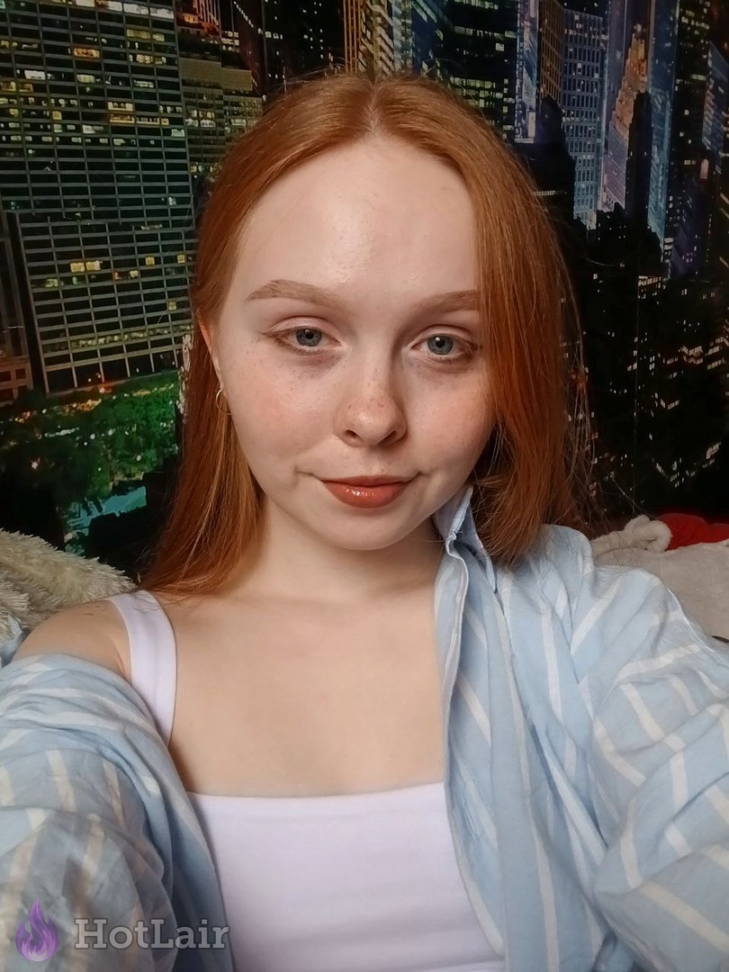 Pretty redhead with blue eyes smiling sweetly in casual top selfie