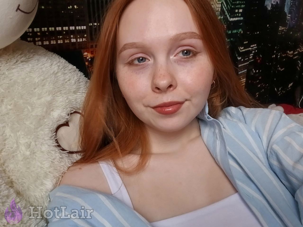 Cute freckled redhead smiling in light blue striped shirt close-up