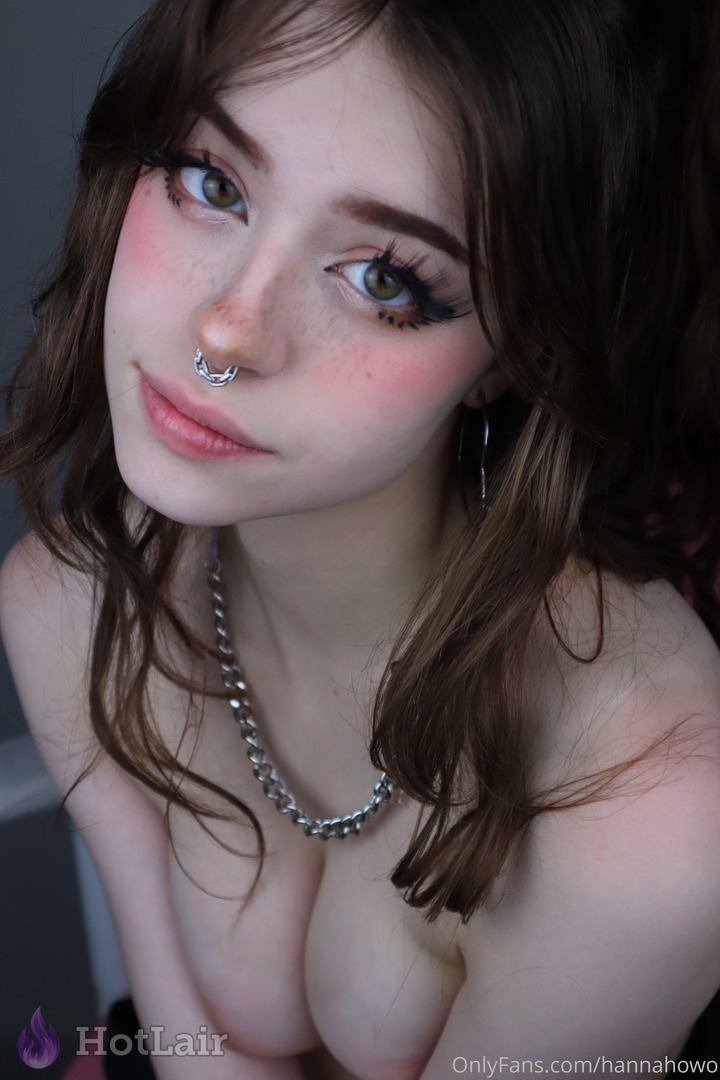 Gorgeous close-up portrait of brunette with heavy makeup, septum piercing and chain necklace looking at camera