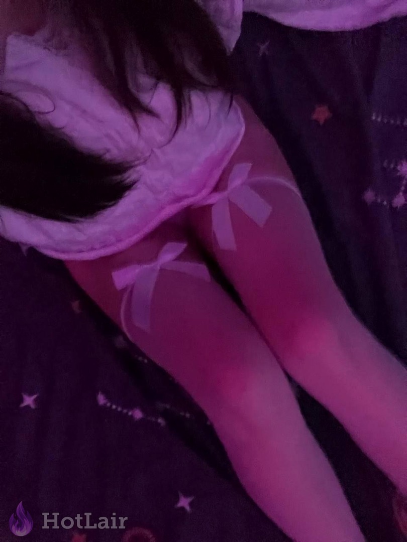 Sexy legs in white stockings with cute pink bows under purple neon lighting on starry bedding