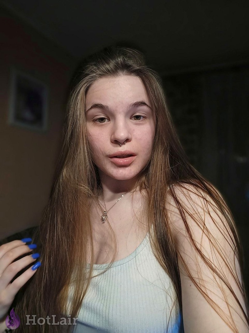 Pretty young brunette with nose ring and long hair posing seductively in white ribbed tank top for selfie